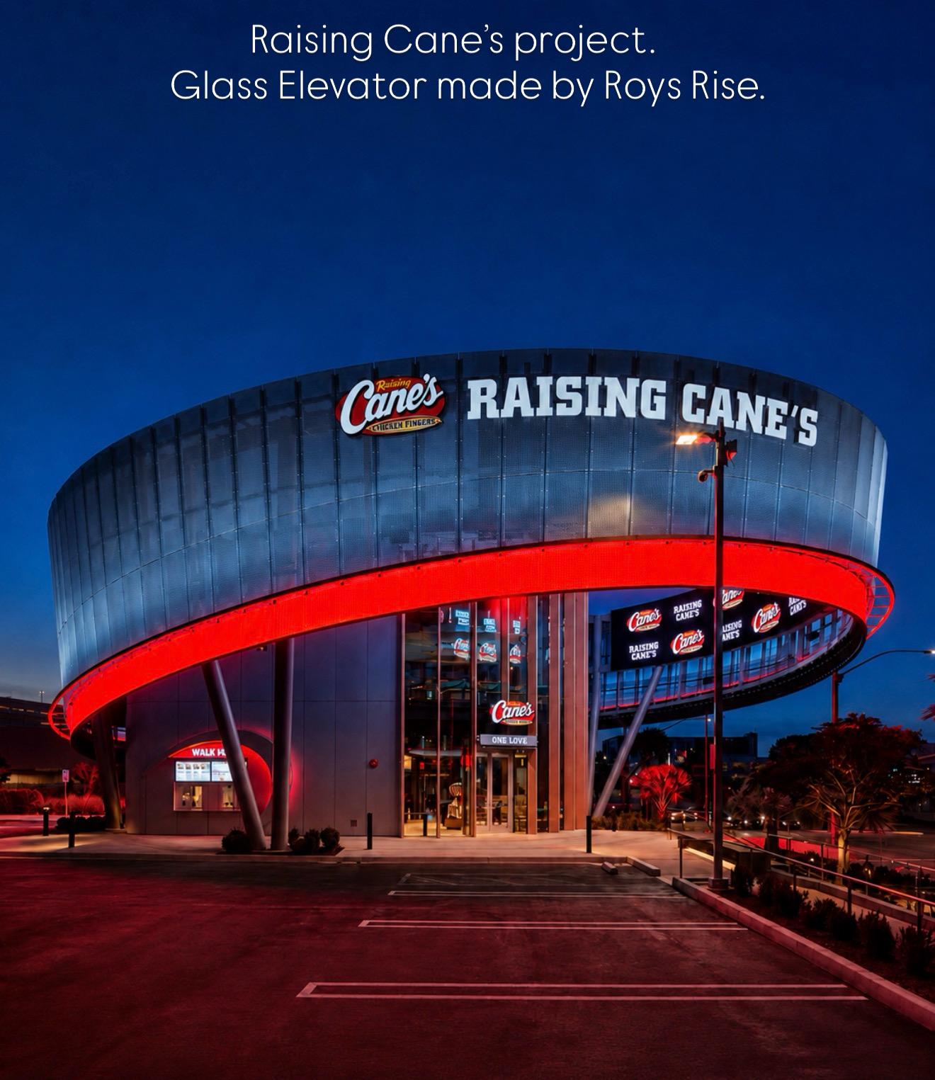 Raising Cane's Inglewood flagship exterior at dusk, with its curved facade and illuminated entrance.